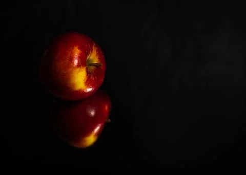 Fresh red apple reflection on black mirror surface. Close up Stock Photos