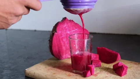 Fresh red beetroot juice being strained into a glass on a wooden board Видео 329975620