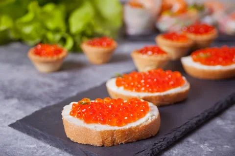 Fresh red caviar on bread on the black plate. Sandwiches with red caviar. Stock Photos