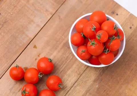 Fresh red cherry tomatoes in a white bowl on wooden table Stock Photos