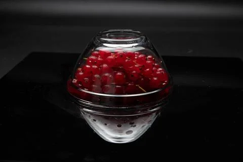 Fresh red currants contained inside a glass dome bowl with a sharp reflection Stock Photos