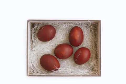 Fresh red eggs and some straw in a wooden crate on a white background. Chicke Foto stock