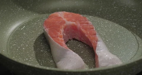 Fresh red fish fillet is fried in a pan. Close-up, slow motion shot Stock Footage 249984599