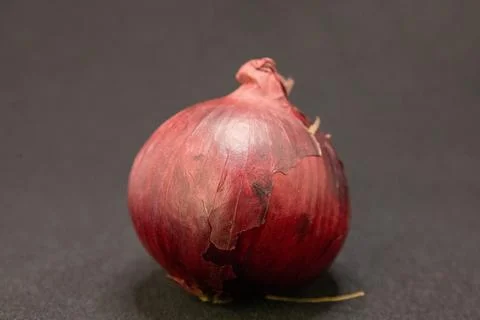 A fresh red onion, a versatile culinary ingredient, is showcased on a dark ba Stock Photos
