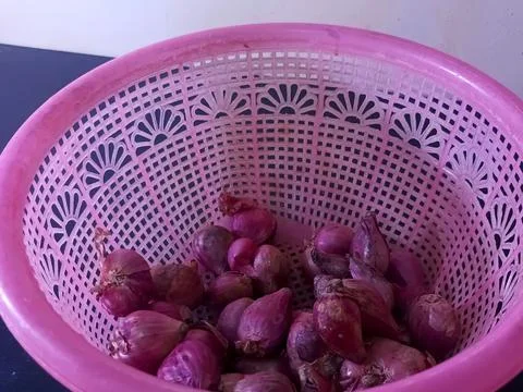 Fresh Red Shallots or Small Onions in a Pink Plastic Basket Top View 스톡 사진