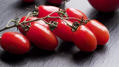 Fresh red tomatoes on black stone surface in motion Video stock 120584754
