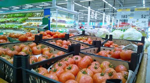 Fresh red tomatoes in boxes. Vegetables on supermarket shelves for sale. Stock Photos