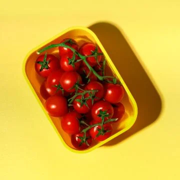 Fresh red tomatoes in a container on a yellow background. Foto stock