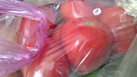 Fresh red tomatoes packed inside a clear thin plastic bag Stock Photos