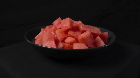 Fresh red watermelon cubes sliced in a dark bowl in front of studio black Stock Footage 314559933