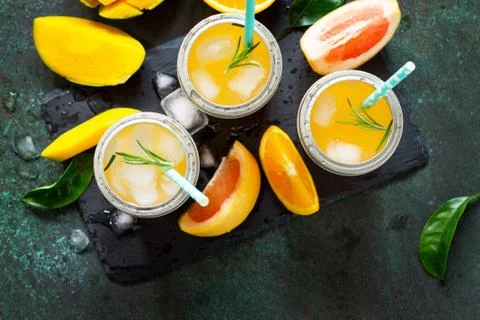 Fresh refreshing summer drinks. Multifruit drinks of citrus and mango with ic Stock Photos