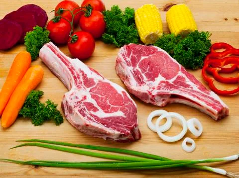 Fresh rib eye with bone with vegetables on wood background. food Stock Photos