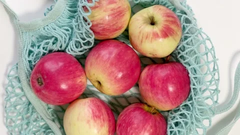 Fresh ripe apples in a ecological zero-waste net bag placed on white background Stock Footage 219918358
