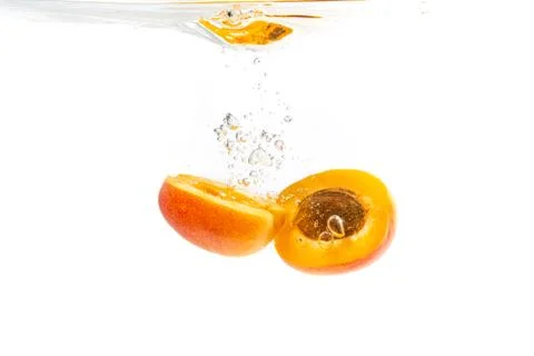 Fresh ripe apricot split in half falling in the clear water Stock Photos