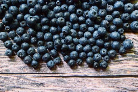 Fresh ripe blueberries scattered on a rustic wooden surface with copy space 스톡 사진
