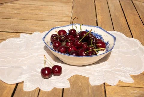 Fresh Ripe Cherries in Sunlight on a Rustic Cottage Garden Table Foto stock