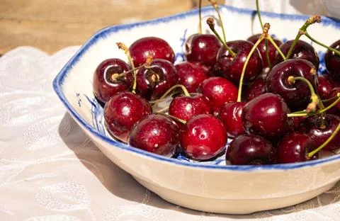 Fresh Ripe Cherries in Sunlight on a Rustic Cottage Garden Table Foto stock