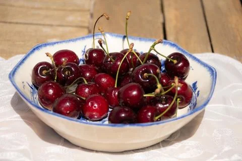 Fresh Ripe Cherries in Sunlight on a Rustic Cottage Garden Table Foto stock