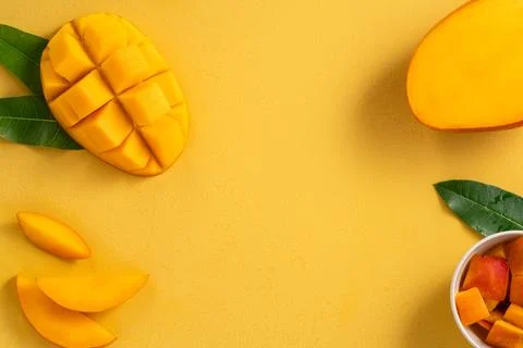 Fresh ripe cut mango fruit slices on yellow background. Stock Photos