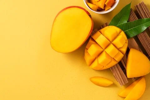 Fresh ripe cut mango fruit slices on yellow background. Stock Photos