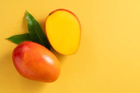 Fresh ripe cut mango fruit slices on yellow background. Stock Photos