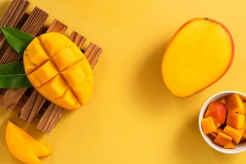 Fresh ripe cut mango fruit slices on yellow background. Stock Photos