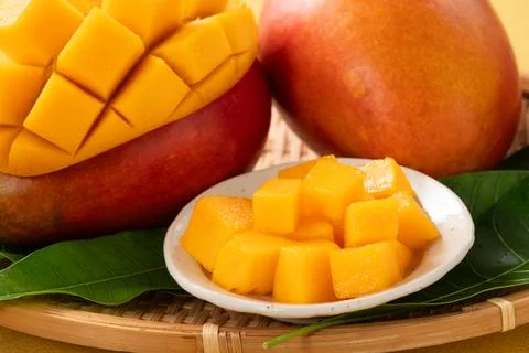 Fresh ripe cut mango fruit slices on yellow background. Stock Photos