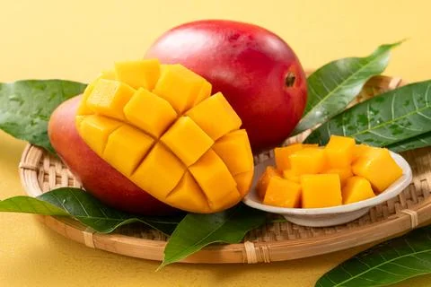 Fresh ripe cut mango fruit slices on yellow background. Stock Photos