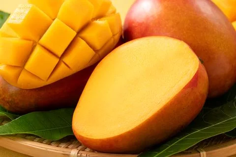 Fresh ripe cut mango fruit slices on yellow background. Stock Photos