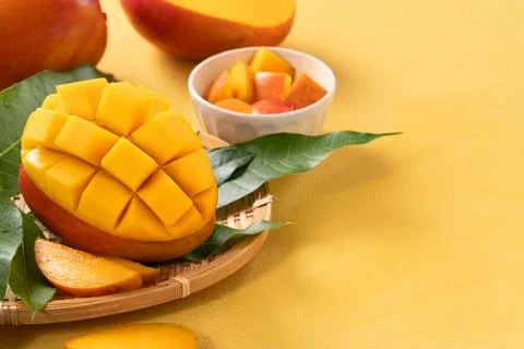 Fresh ripe cut mango fruit slices on yellow background. Stock Photos