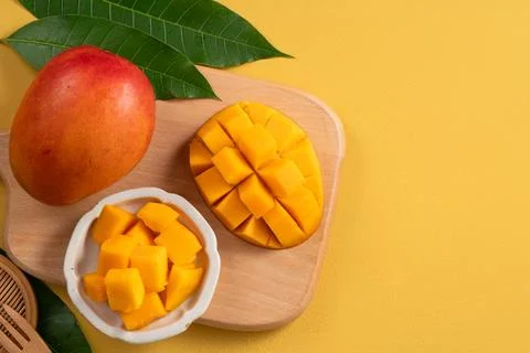 Fresh ripe cut mango fruit slices on yellow background. Stock Photos