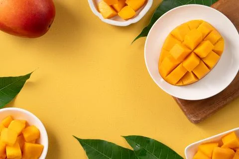 Fresh ripe cut mango fruit slices on yellow background. Stock Photos