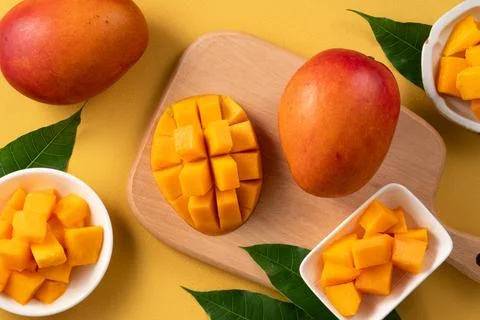 Fresh ripe cut mango fruit slices on yellow background. Stock Photos