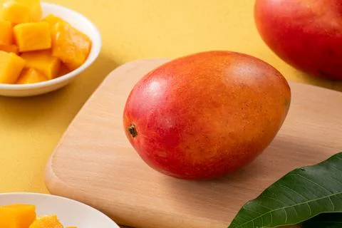 Fresh ripe cut mango fruit slices on yellow background. Stock Photos