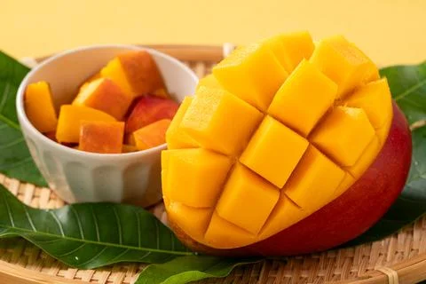 Fresh ripe cut mango fruit slices on yellow background. Stock Photos