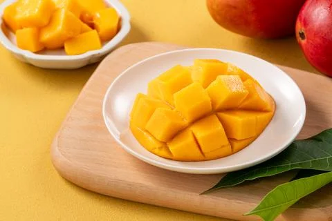 Fresh ripe cut mango fruit slices on yellow background. Stock Photos