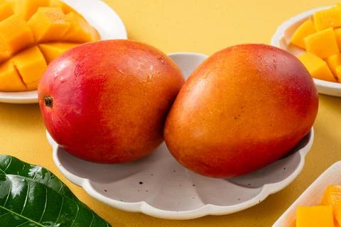 Fresh ripe cut mango fruit slices on yellow background. Stock Photos