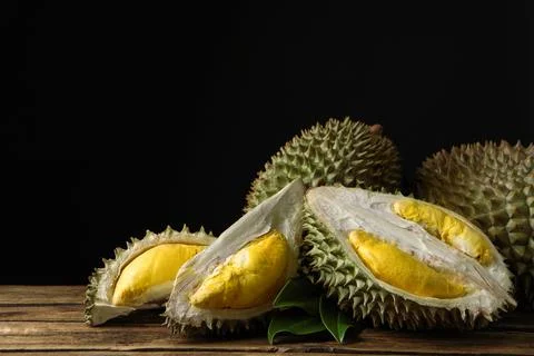 Fresh ripe durian fruits on wooden table against black background Stock Photos