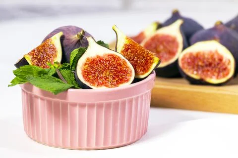 Fresh Ripe Fig with mint leaf in pink ceramic bowl on white background, Black Stock Photos