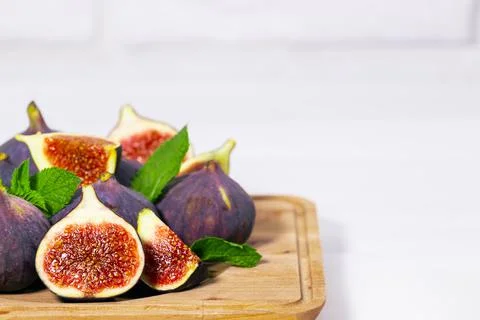 Fresh Ripe Fig with mint leaf on wooden board on white background, Healthy su Stock Photos