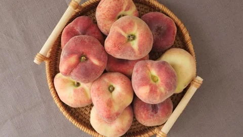 Fresh ripe flat peaches rotating in a wicker basket Stock Footage 339367041