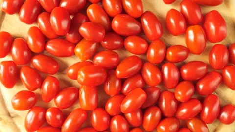 Fresh ripe grape tomatoes rotating on a wooden surface Stock Footage 336038448