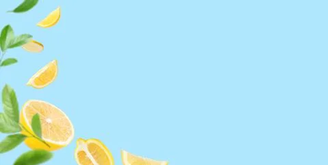Fresh ripe lemons and green leaves falling on light blue background, space fo Stock Photos