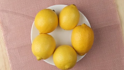 Fresh ripe lemons rotating on a white plate Stock Footage 343435455