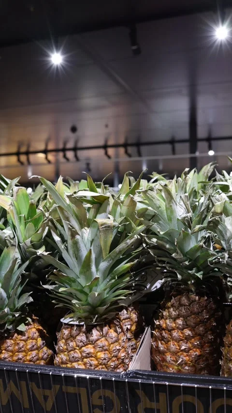 Fresh ripe pineapples displayed in the produce section of a grocery store Stock Footage 345978614
