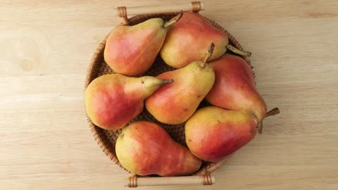 Fresh ripe red pears rotating in basket on wooden table Stock Footage 348309204