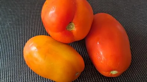 Fresh ripe Roma tomatoes on a dark background. Organic red vegetables for Stock Photos