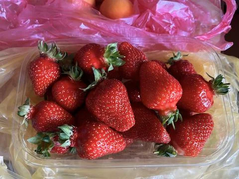 Fresh ripe strawberries in plastic container close up on kitchen table Stock Photos