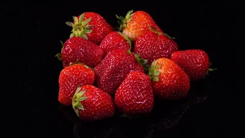 Fresh ripe strawberry rotating with reflection on black mirror background in 4K Vidéo 77682696