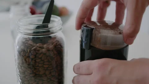 Fresh roasted coffee beans pouring in a grinder from glass jar Video stock 145368028